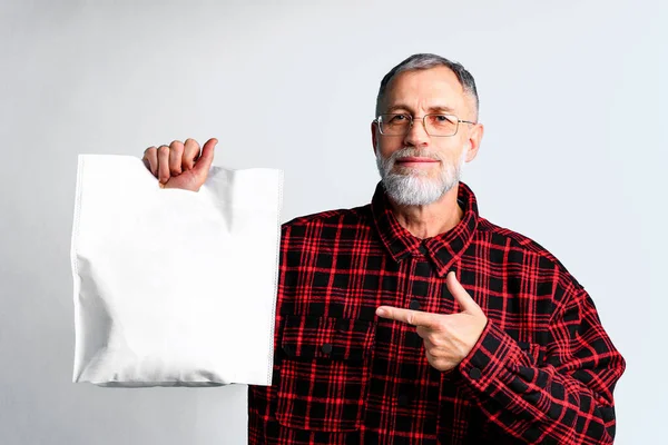 Hombre maduro está sosteniendo el bolso ecológico textil blanco sobre fondo blanco —  Fotos de Stock