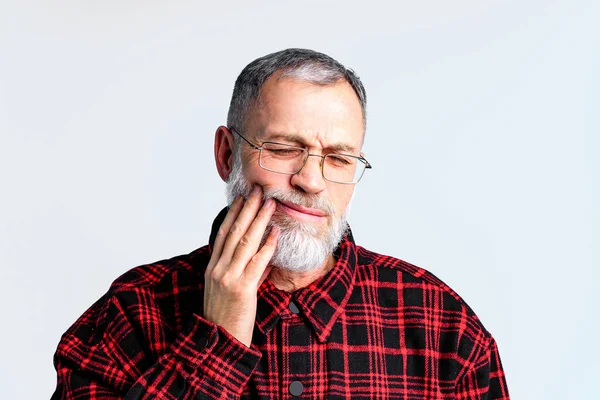 Retrato de hombre maduro aislado en estudio de fondo gris que sufre de dolor dental severo, cerrando los ojos para aliviar el dolor —  Fotos de Stock