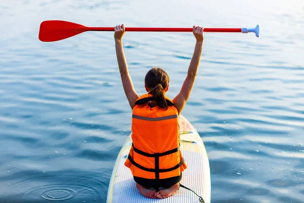 Young woman in orange life jacket on supboard at river — Stock Photo, Image