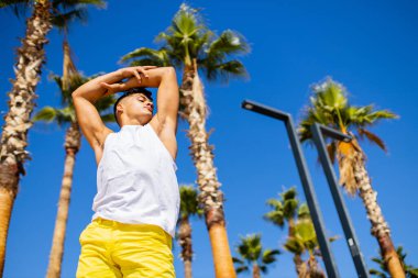 Güneşli bir günde plajda köpük kremi kullanan iri yarı, Brezilyalı bir adam.