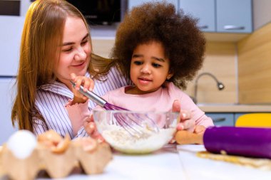 Polietnik aile bisküvi pişiriyor, kahvaltıyı evde birlikte hazırlıyorlar.