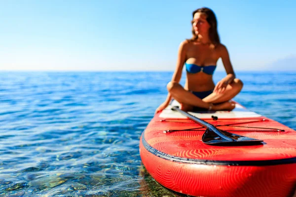 Schöne Frau praktiziert Yoga auf Paddel und Surfbrett — Stockfoto