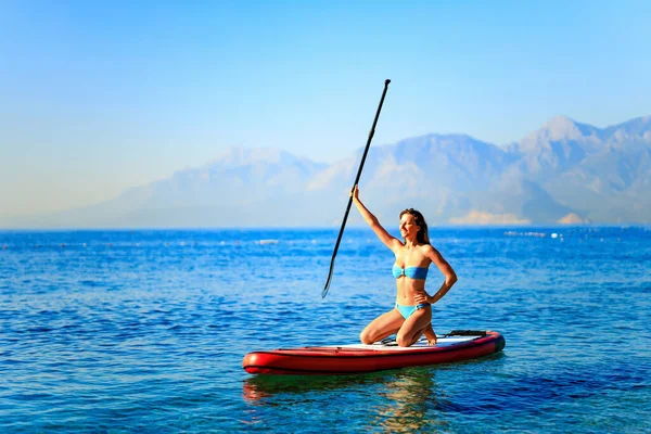 Frau paddelt auf Surfbrett mit Bergen im Hintergrund — Stockfoto