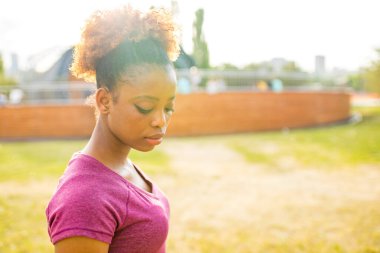 Üzgün, kıvırcık saçlı, dışarıda parka bakan Afro-Amerikalı kadın.