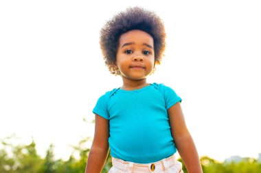 Parkta kıvırcık saçları olan çok kültürlü, güzel küçük bir kız.