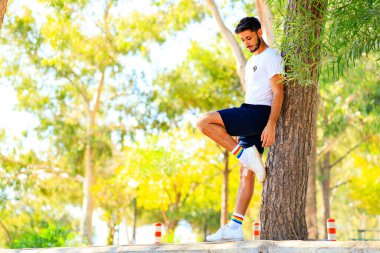 Gökkuşağı rozeti ve çorapları olan beyaz gömlekli yakışıklı bir adam.