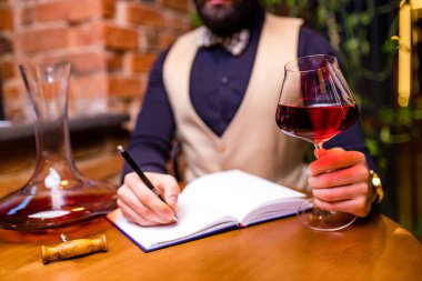 Mutlu erkek şarap üreticisi bir tat alıyor ve kırmızı şarap kalitesini kontrol ediyor.