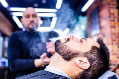 Arap yakışıklı sakallı adam berber dükkanında saçını kestiriyor.