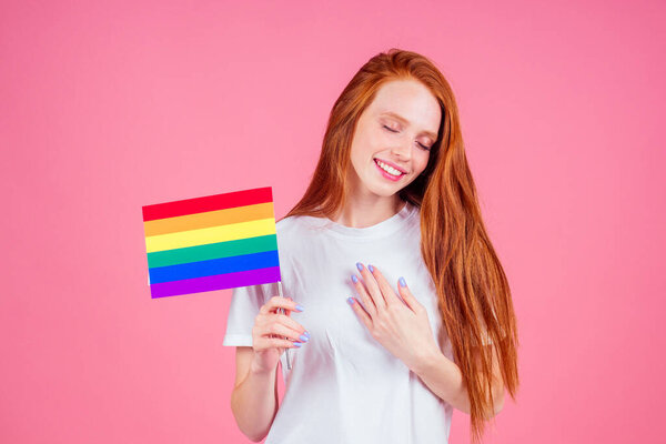 рыжая рыжая женщина с красочным флагом в студии розовый фон