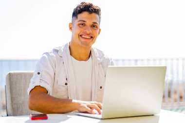 Mutlu Arjantinli öğrenci dışarıda dizüstü bilgisayarla günah işliyor ve mutlu görünüyor.