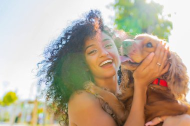 Neşeli, uzun, kıvırcık saçlı, Amerikan cocker köpeğiyle yaz parkında oynayan kadın.
