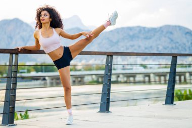 İspanyol Brezilya Açık hava sporları alanında bacağını ve el kaslarını gevşetiyor.