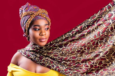 Kırmızı stüdyo arka planında makyajlı ve ipek sarıklı otantik çok kültürlü yarış kadını.