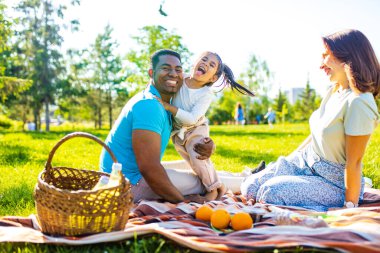 Latin baba ve Avrupalı anne güneşli bir günde piknikte sevimli bir çocukla .