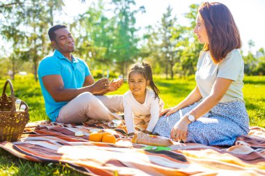 Latin baba ve Avrupalı anne güneşli bir günde piknikte sevimli bir çocukla .