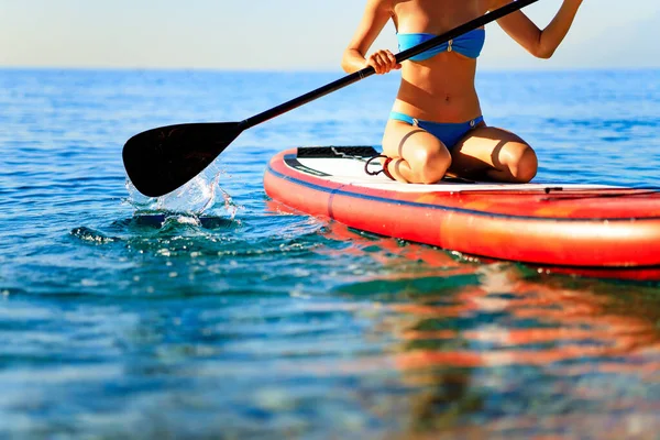 sporty fitness woman on SUP board at sunny nice day on sea .