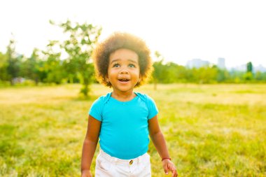 Gün batımında parkta tek başına yürüyen sevimli, küçük, çok kültürlü yarış kızı..