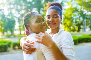 İki Afro-Amerikalı kadın, yaz parkında parlak bir erkekle Wtite elbisesiyle evliliklerini kutluyorlar. .