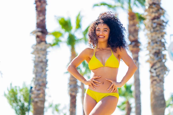multicultural race smiling curly woman in swimming suit standing at the beach.