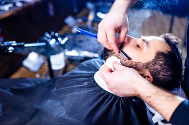 Berber dükkanında berbere saçını kestiren İspanyol sakallı adam..