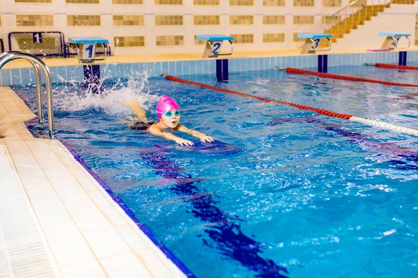 Down syndrome in swimming cap training in seimming pool sport club with trainer .