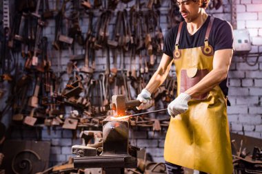 Otantik demirci, karanlık stüdyoda metal bir ürün üretiyor..