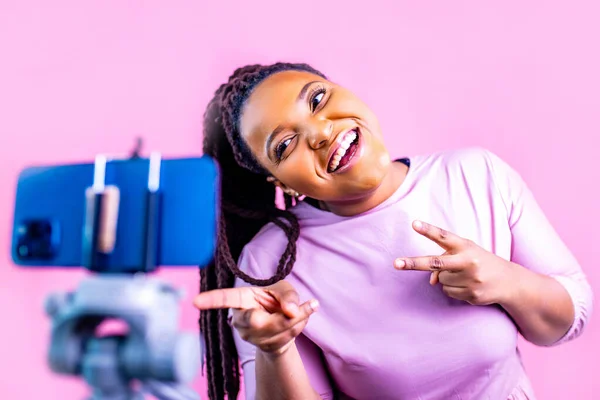 Saçları örgülü, sarı saçlı İspanyol kadın stüdyoda aboneleriyle telefonda konuşurken pembe elbise giyiyor. .