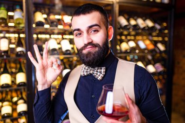 Mutlu erkek şarap üreticisi bir tat alıyor ve kırmızı şarap kalitesini kontrol ediyor. .