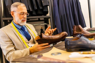 Bir atölyede el yapımı erkek ayakkabıları ve kemeri gösteren yaşlı bir ayakkabıcı..