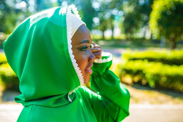 multicultural race islamic woman in green cotton hijab with gorgeous make up outdoors in summer park.