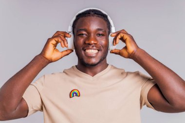 Beyaz kulaklıklı Meksikalı adam bej tişörtlü müzik dinliyor. .