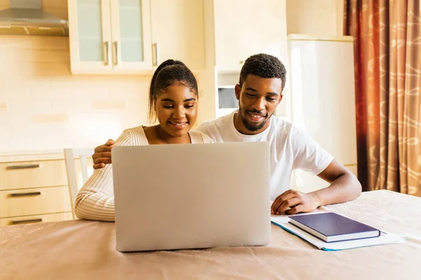 African american couple managing finances bank and using laptop at kitchen.