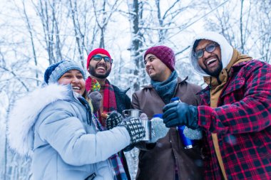Mutlu genç Hintli arkadaşlar sıcak çayla ısınır. .