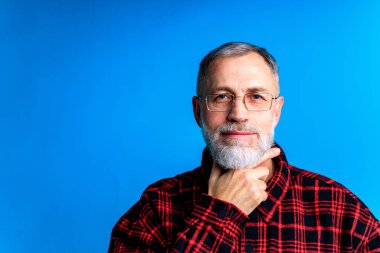 Yaşlı yakışıklı adam önemli seçimler yapıyor Blue Backgrond Stüdyosu.