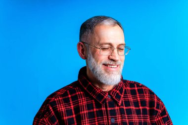 Mavi stüdyo arka planına bakan zeki utangaç bir adamın yakın plan portresi..