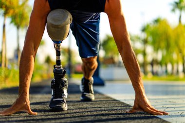 Protez bacaklı engelli bir sporcu gün batımında sahilde koşmaya başlıyor..