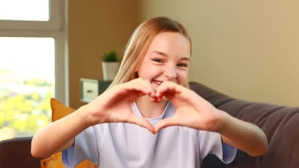 Heureuse Petite Fille Montrant Geste Forme Coeur Dans Salon Confortable — Video