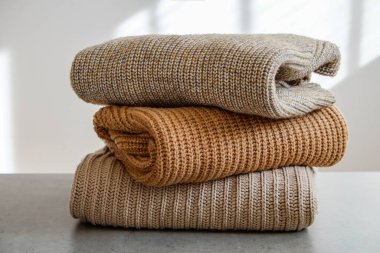 Bir sürü örülmüş pastel renkli süveter farklı örgü desenleri yığılmış, açıkça görülebilen doku. Şık sonbahar kış mevsimi örgü giysileri. Kapat, metin için boşluk kopyala.