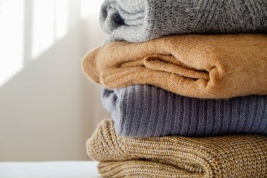 Bir sürü örülmüş pastel renkli süveter farklı örgü desenleri yığılmış, açıkça görülebilen doku. Şık sonbahar kış mevsimi örgü giysileri. Kapat, metin için boşluk kopyala.