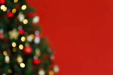 Süslü Noel ağacını, izole edilmiş kırmızı zemin üzerinde bokeh etkisi olan yumuşak sarı ışıklarla bulanıklaştırmış. Kapat, boşluğu kopyala.