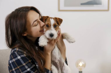 Sevimli dört aylık tel saçlı yavru köpeğiyle oynayan güzel bir kadının portresi. Sert kaplamalı sevimli kız eğleniyor. Arkaplan, kapat, boşluğu kopyala.