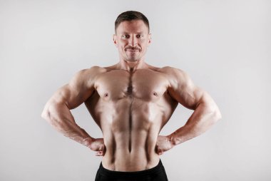 Professional bodybuilder posing over isolated white background. Front Lat Spread pose. Studio shot of a fitness trainer flexing the muscles. Close up, copy space. clipart