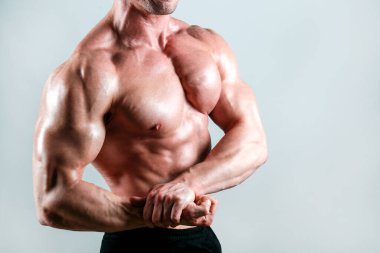 İzole edilmiş beyaz arka planda poz veren profesyonel vücut geliştirici. Spor salonundaki antrenörün kaslarını esnetirkenki görüntüsü. Göğüs kenarı pozisyonu. Kapat, boşluğu kopyala.