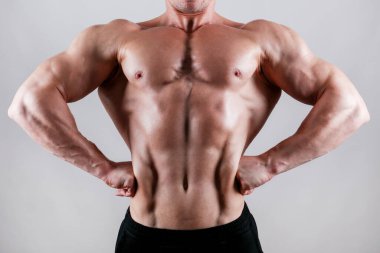 İzole edilmiş beyaz arka planda poz veren profesyonel vücut geliştirici. Ön Lat Spread pozu. Spor salonundaki antrenörün kaslarını esnetirkenki görüntüsü. Kapat, boşluğu kopyala.