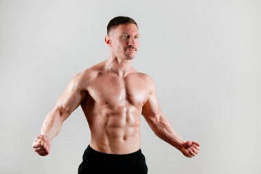 İzole edilmiş beyaz arka planda poz veren profesyonel vücut geliştirici. Spor salonundaki antrenörün kaslarını esnetirkenki görüntüsü. Kapat, boşluğu kopyala.