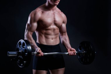 Profesyonel vücut geliştirici, siyah arka planda kıvrımlı halterle biceps egzersizi yapıyor. ez Bar 'lı bir fitness modelinin stüdyo fotoğrafı. Kapat, boşluğu kopyala.