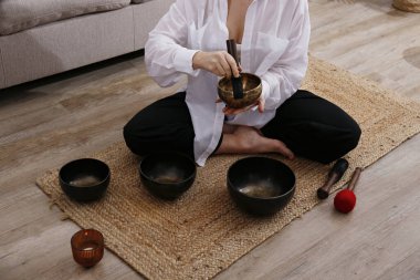 Stüdyosunda ses iyileştirme seansı yapan bir kadın. Yogini, Tibet şarkı kasesi kullanarak meditasyon müziği çalıyor. Kapat, kopyala boşluk, arkaplan.