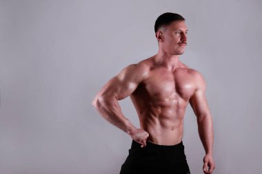 İzole edilmiş beyaz arka planda poz veren profesyonel vücut geliştirici. Spor salonundaki antrenörün kaslarını esnetirkenki görüntüsü. Kapat, boşluğu kopyala.