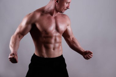İzole edilmiş beyaz arka planda poz veren profesyonel vücut geliştirici. Spor salonundaki antrenörün kaslarını esnetirkenki görüntüsü. Kapat, boşluğu kopyala.