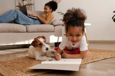Farklı yaşlarda iki güzel siyah kız sevimli tel saçlı Jack Russel teriyerleriyle evde oynuyorlar. Sert kaplamalı sevimli kız kardeşler eğleniyor. Arkaplan, kapat, boşluğu kopyala.